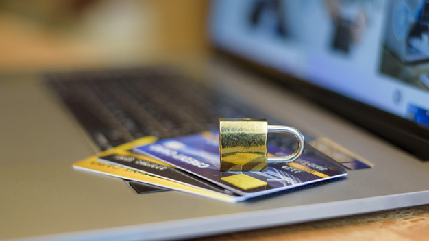 LGPD representada por cartões em cima de um notebook e embaixo de um cadeado dourado